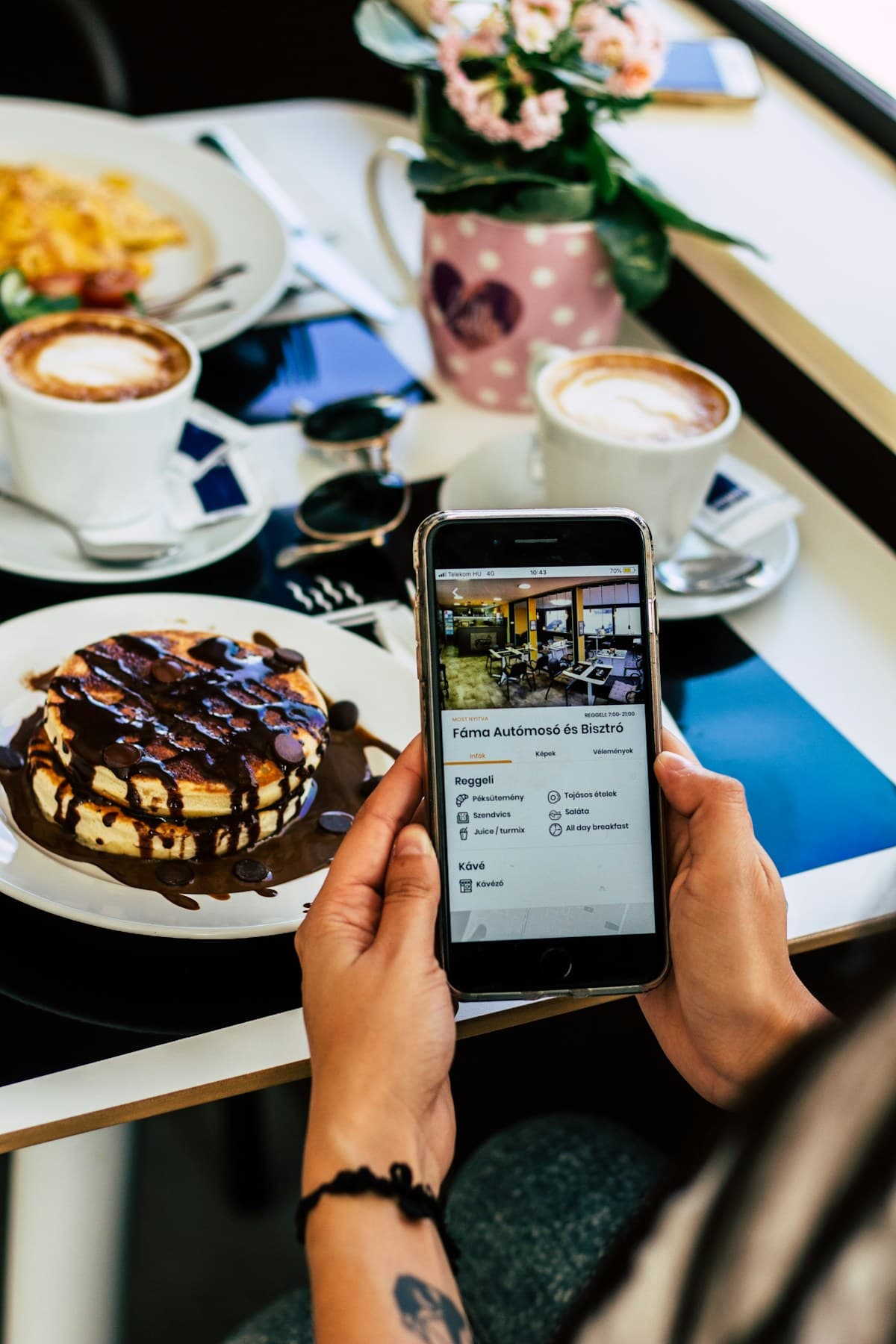 Kafe masasında telefondan dijital menüye bakan müşteri