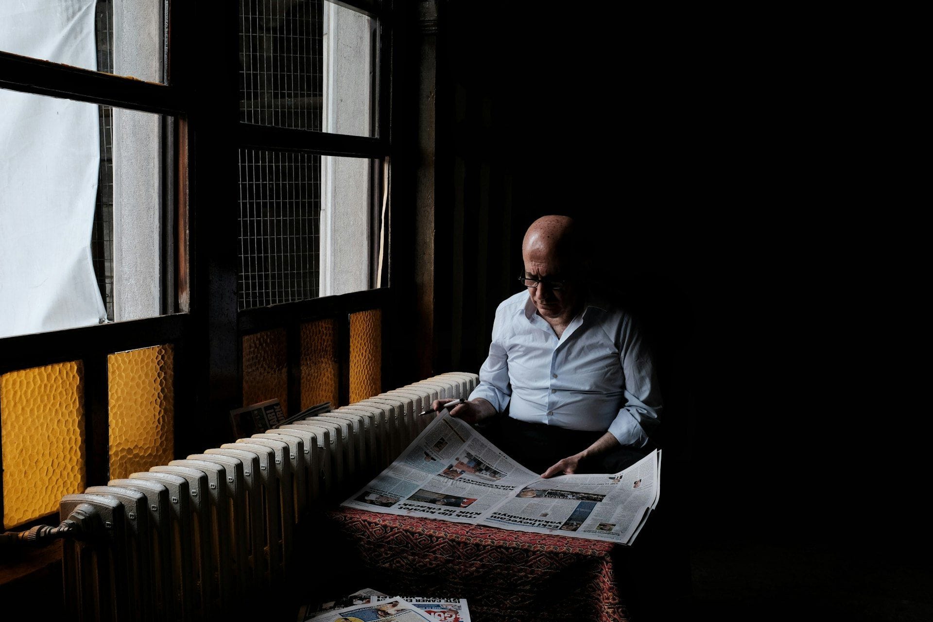 Pencere kenarında gazete okuyan adam