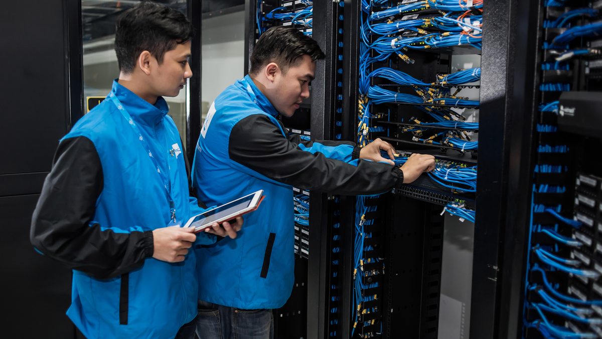 Veri merkezinde sunucu dolabında çalışan teknisyenler (Technicians at a data center rack)